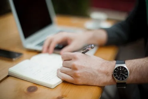 A man writing in his gift letter in his notebook.