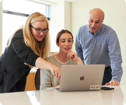 Three colleagues reviewing information together on a laptop during a planning meeting
